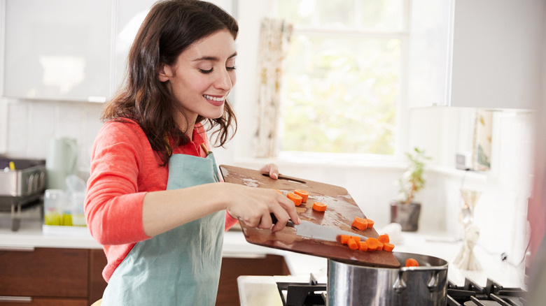 Woman putting carrots in pot 