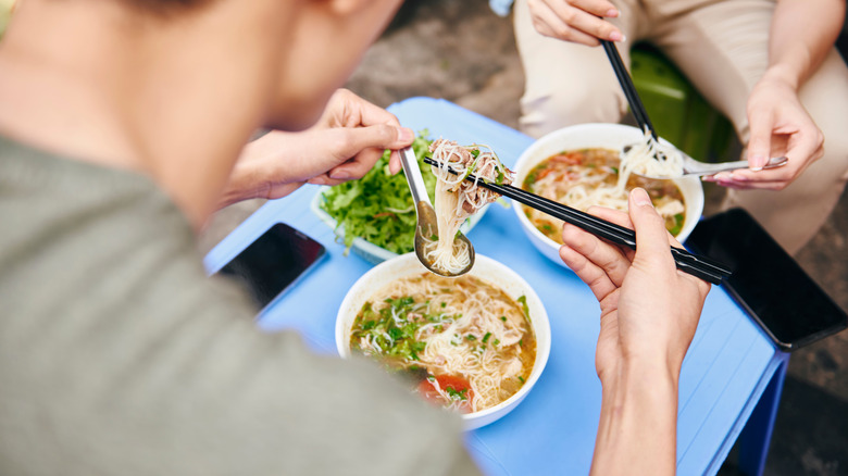 Two people eating pho