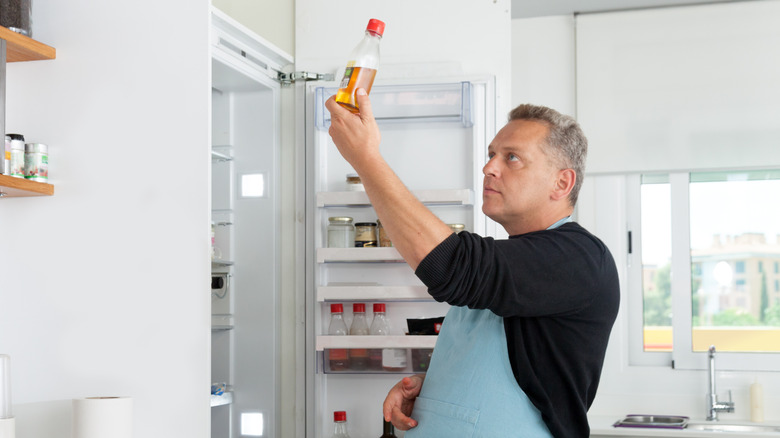 man checking bottle from refrigerator