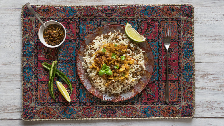 Embroidered placemat with a plate of mujadarra, made from white rice, green lentils, and fried onions