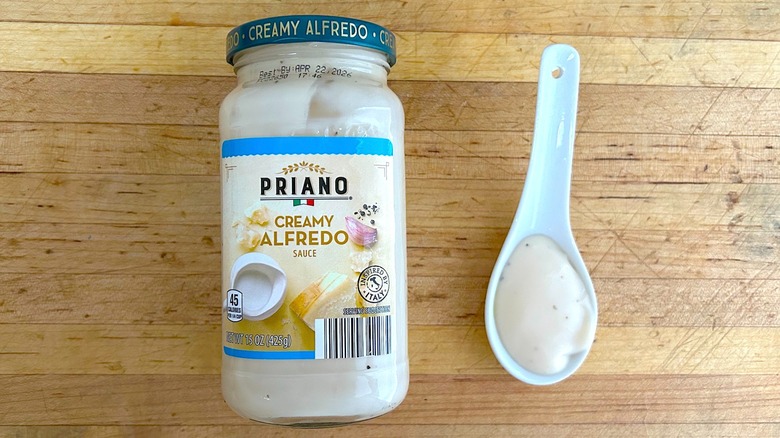 Jar and spoonful of Priano Creamy Alfredo Sauce