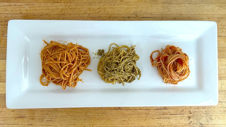 Rectangular plate with spaghetti in marinara, pesto, and rosso pesto