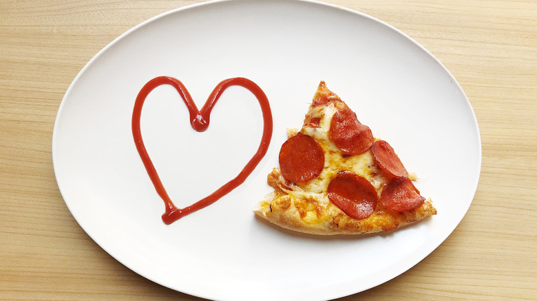 Pizza slice and ketchup in heart shape