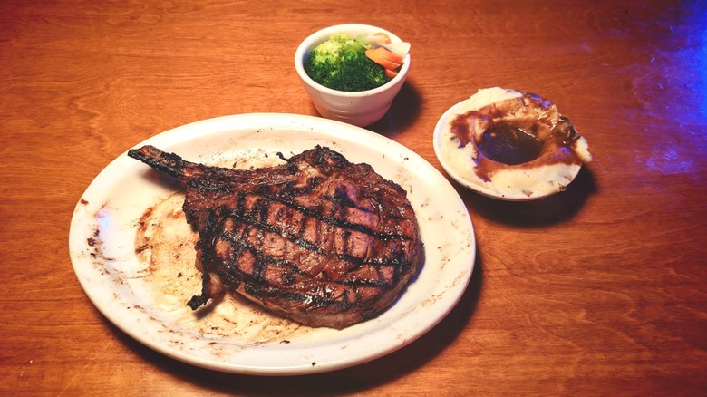 Texas Roadhouse bone-in ribeye on a plate with sides