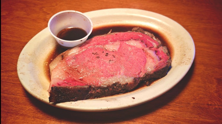 Texas Roadhouse prime rib on a plate with cup of au jus