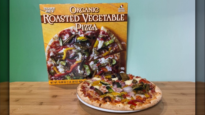 Baked pizza with roasted vegetables, next to the box