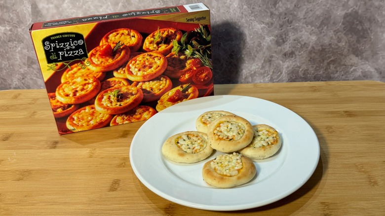 Five mini pizzas on a plate, in front of the box