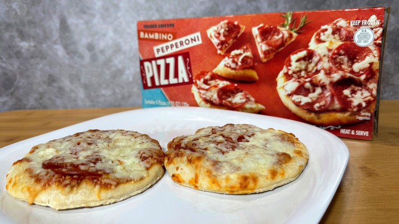 Two small pepperoni pizzas on a plate, next to their box