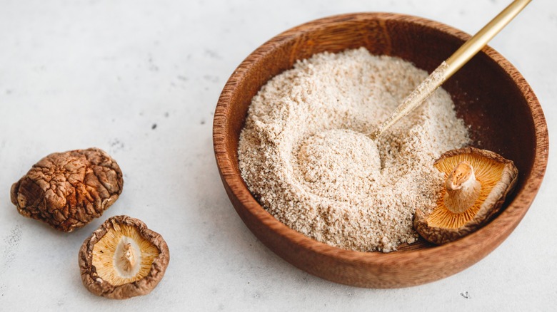 A bowl of dried shiitake mushroom powder next to dried mushrooms