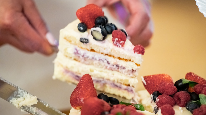 Person slicing berry cake