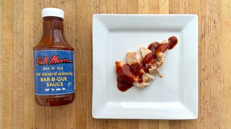 Bottle and square white plate of chicken with Full Moon BBQ Sauce