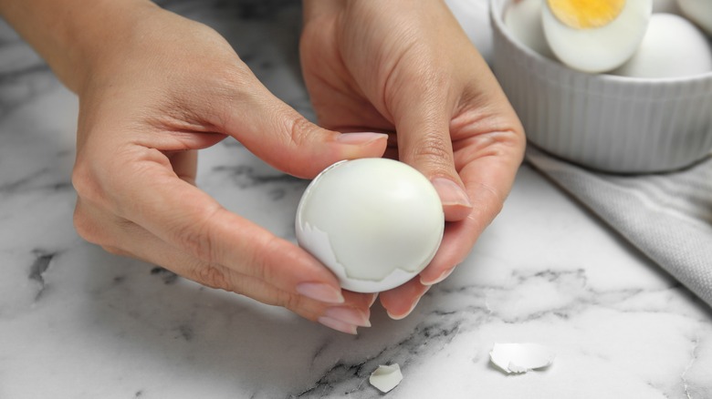 Hands peeling a hard-boiled egg