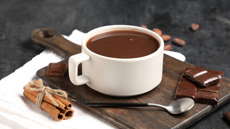 Cup of hot chocolate with cinnamon sticks and chocolate bars