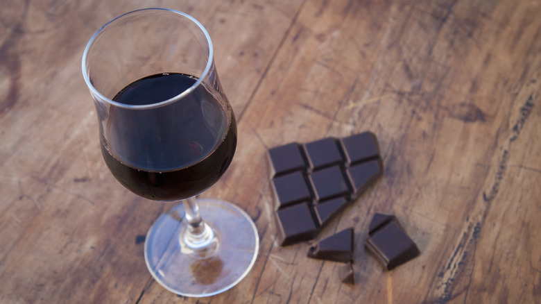 glass of red wine with dark chocolate on wood tabletop