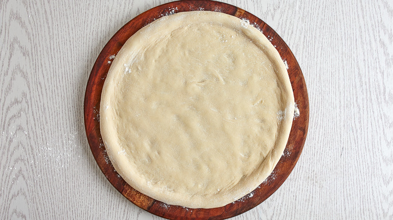 pizza dough rolled out on board