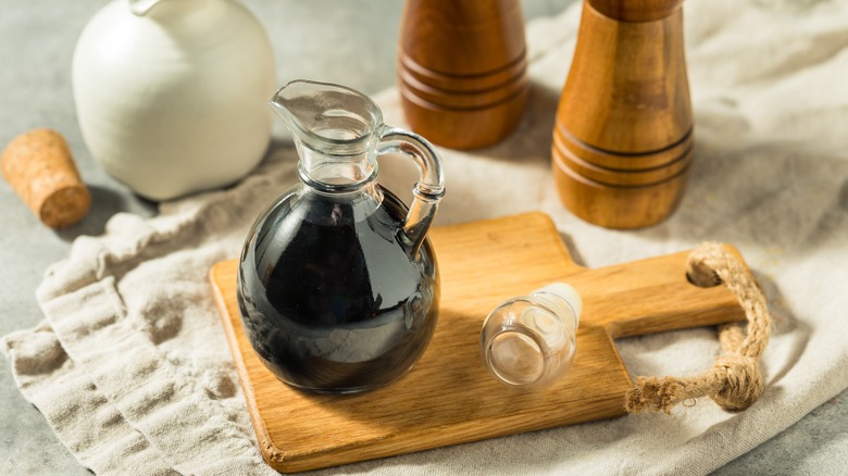 glass jug of balsamic on wood cutting board