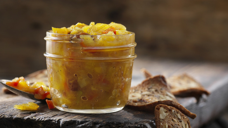 Mango chutney in jar on wooden board