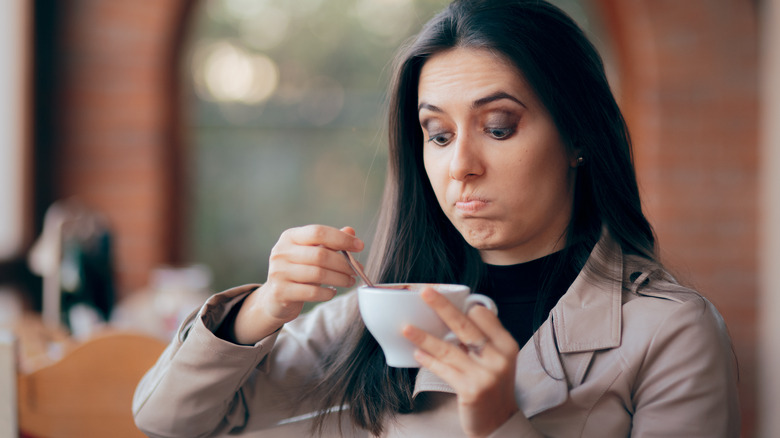 Woman looks disgusted at mug