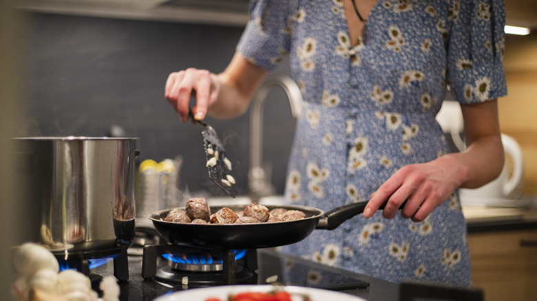 woman frying meatballs on stovetop