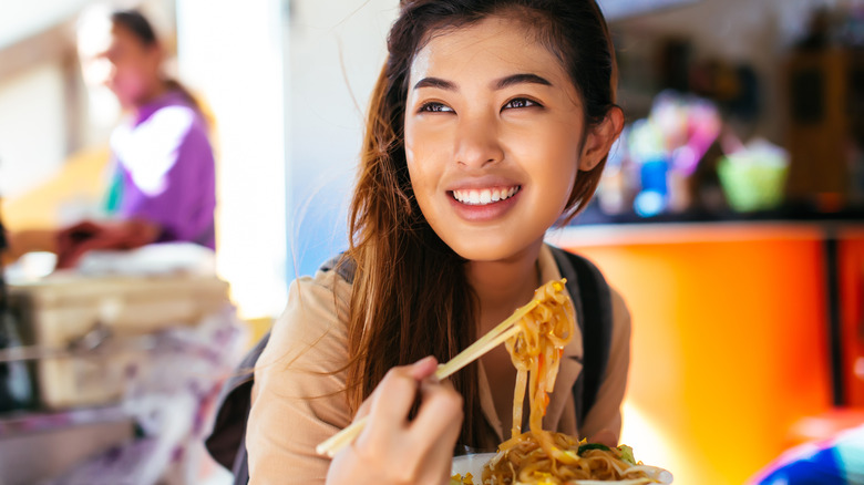 Young woman eating pad thai