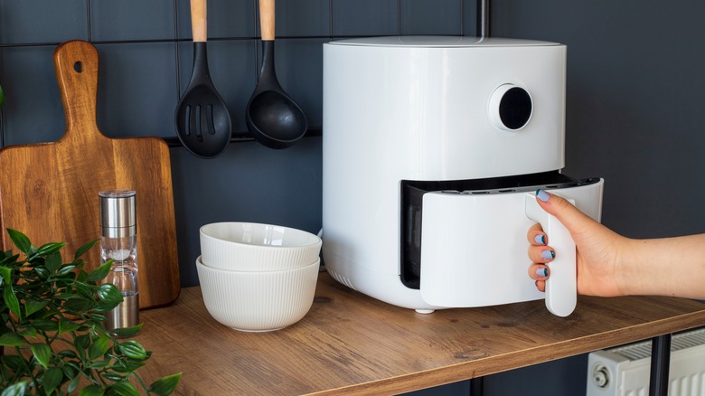 hand using air fryer on kitchen counter