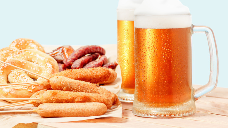 Corn dogs beside German pretzels, sausage, and beer