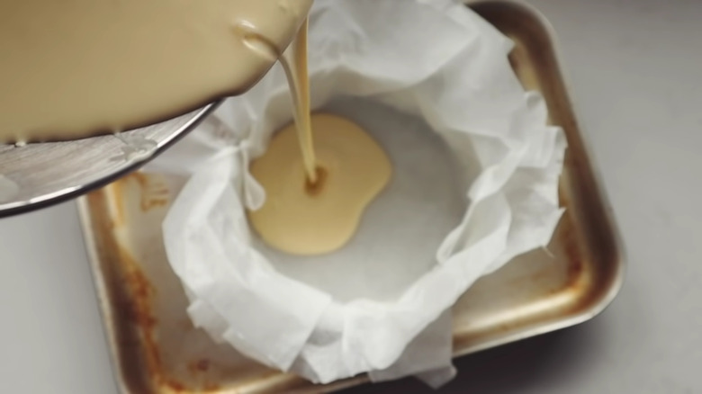 Pouring cheesecake batter into tin