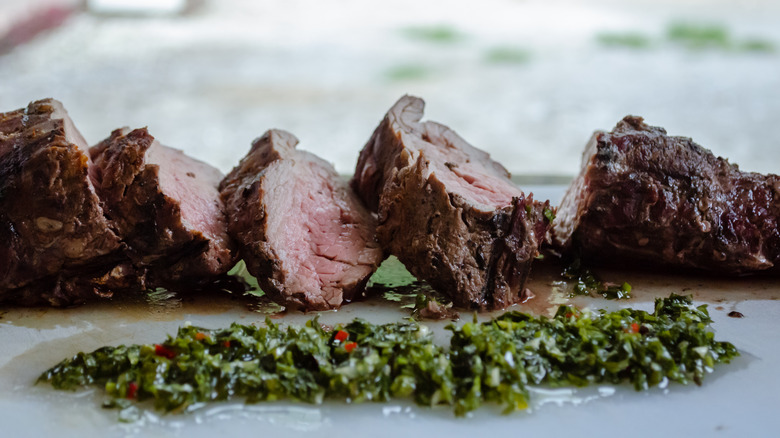 sliced steak and chimichurri on plate