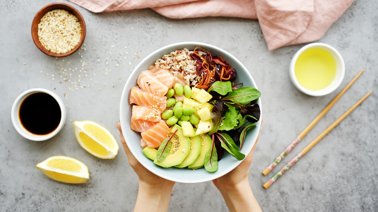 Hands holding poke bowl