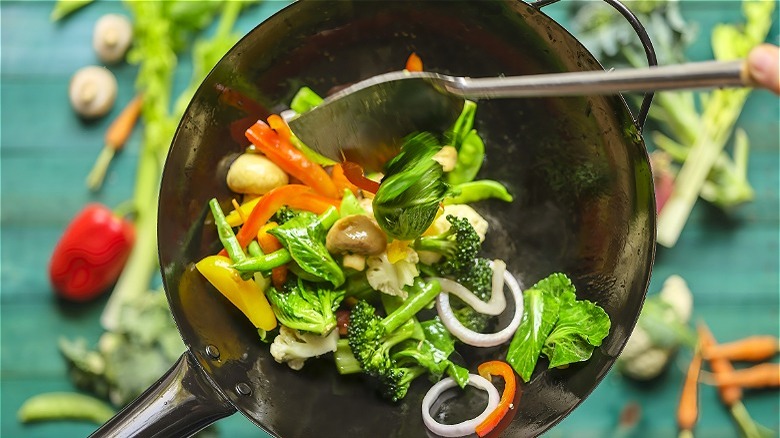 Vegetables and spoon in frying pan 