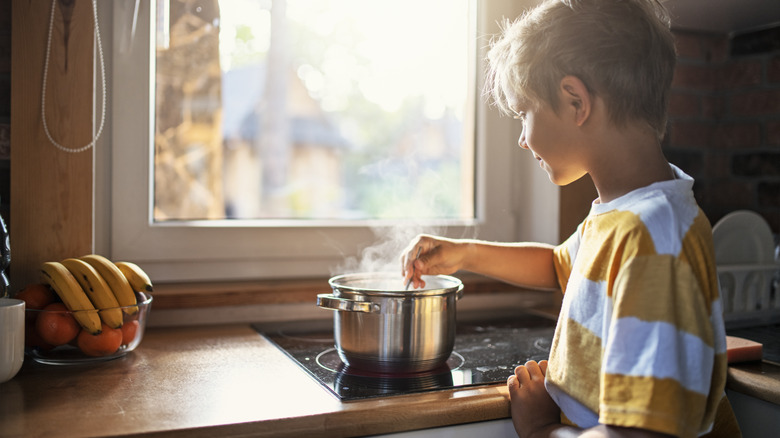 child stirring pot on stove