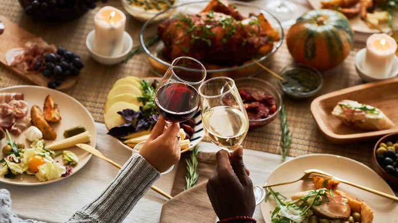 two people clinking wine glasses at a Thanksgiving table