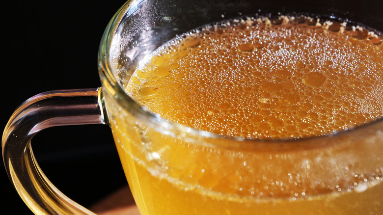 Strained chicken broth in glass cup