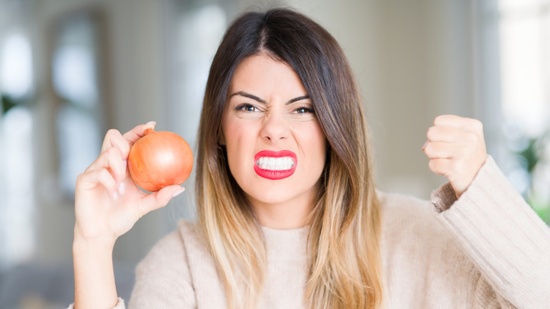 Woman holding onion making face