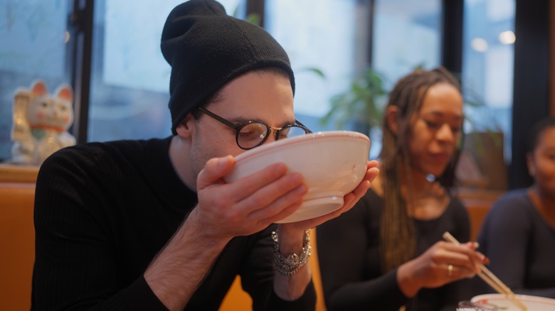 Person drinking soup from bowl