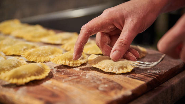 Person sealing ravioli with fork