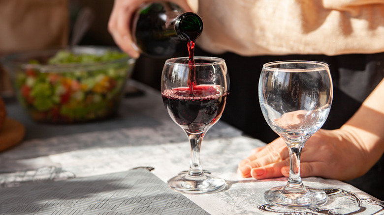 person pouring glass of red wine