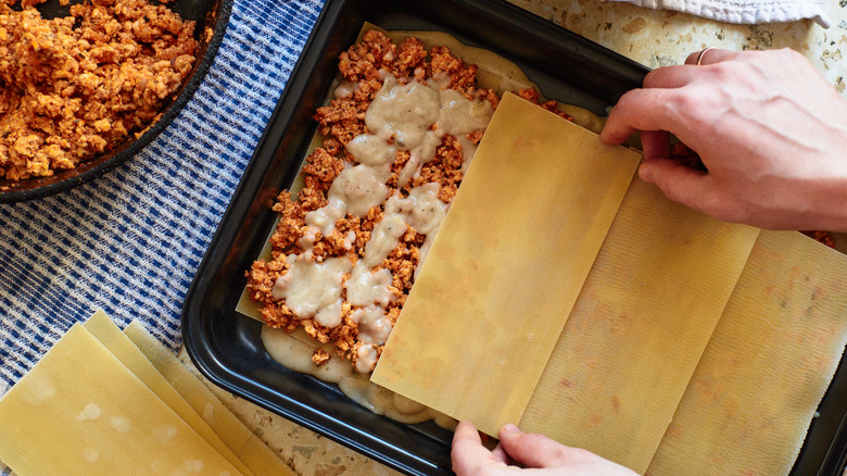 assembling lasagna in baking dish