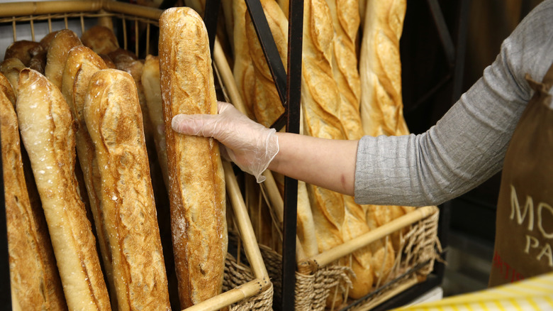 worker selecting baguette from a basket