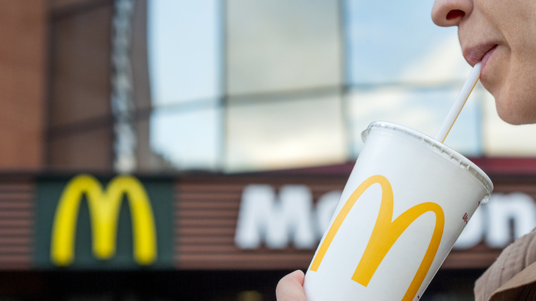 Person sipping a drink from a McDonald's cup