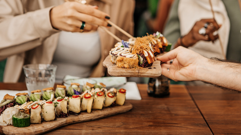 People sharing sushi with soy bottle in background