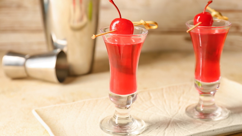 Woo woo cocktail served in shot glasses with a cherry garnish