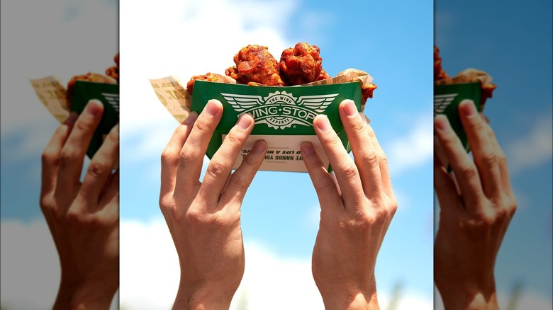 hands holding Wingstop wings