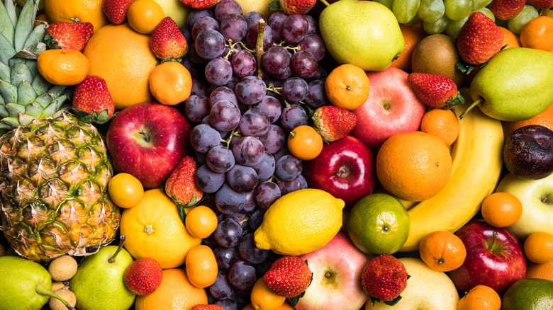 Colourful selection of mixed fruits, including apples, oranges, grapes, bananas, and a pineapple