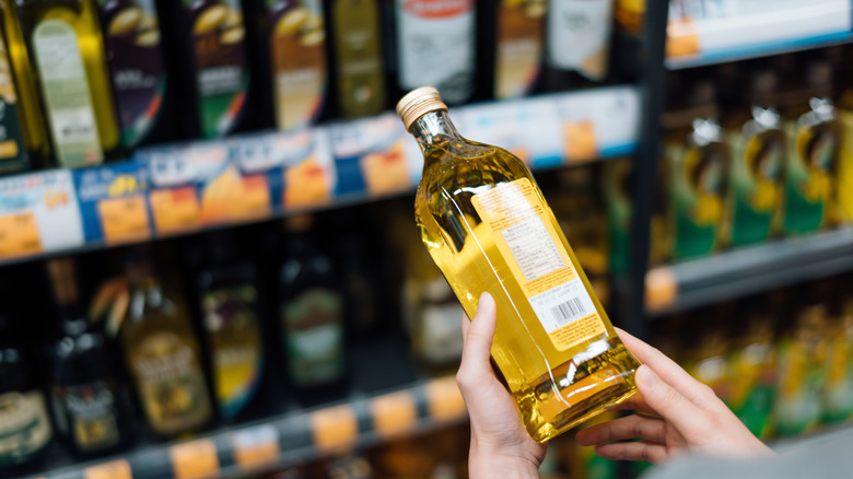 A shopper holding a bottle of oil