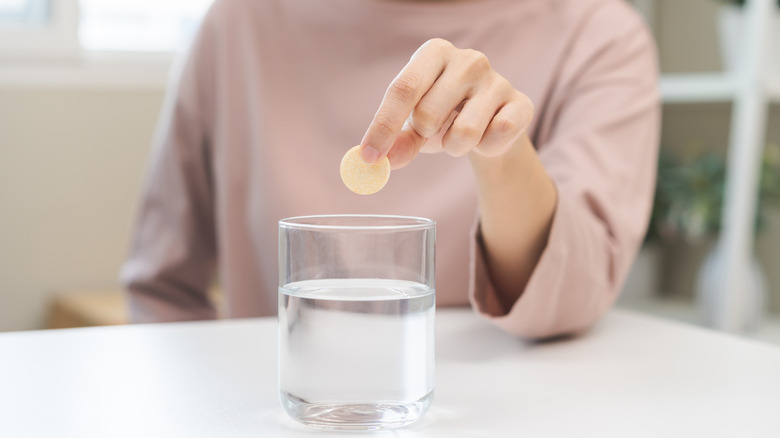 Person dropping tablet into water