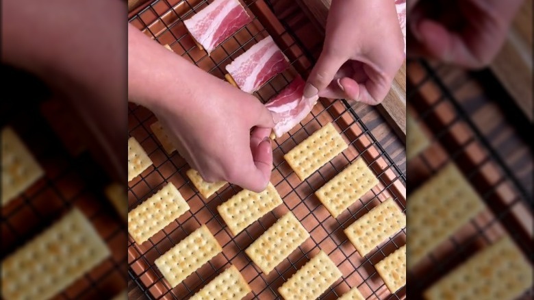 hand prepares bacon crackers