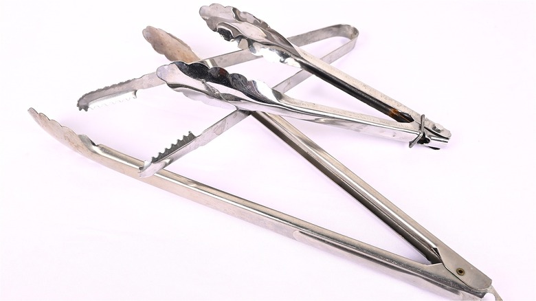 Various metal tongs on white background 