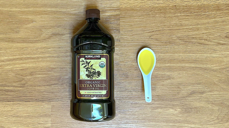 Kirkland organic extra virgin olive oil bottle with white spoonful of oil on wood table