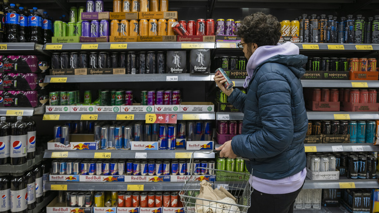 man checking energy drink labels store